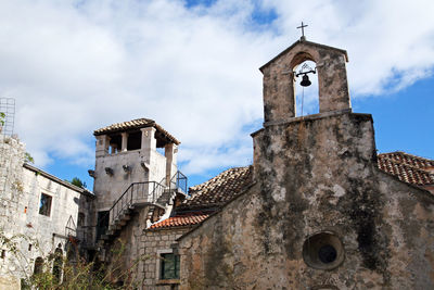 Low angle view of bell tower against cloudy sky