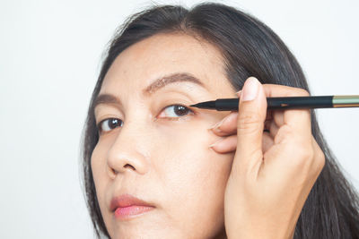 Close-up portrait of young woman making face against white background