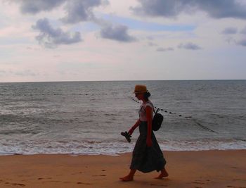 Full length of man walking on beach against sky