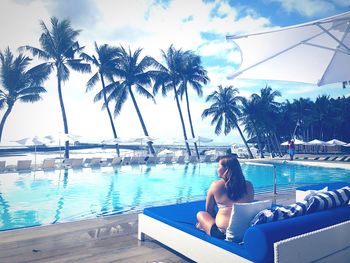 Woman relaxing on swimming pool against sky