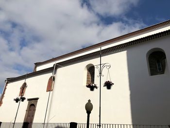 Low angle view of street light by building against sky