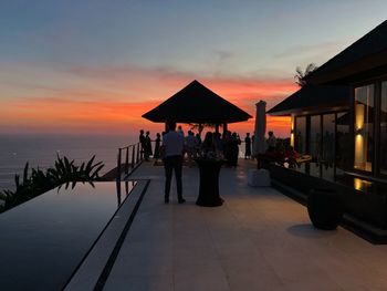 People at beach against sky during sunset