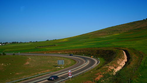 Aerial view of winding road against clear blue sky