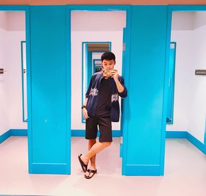 Full length portrait of young man standing against building