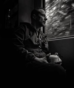 Man drinking coffee sitting against sky