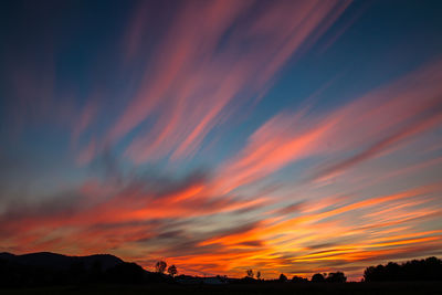 Silhouette landscape against dramatic sky during sunset