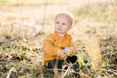 Portrait of cute baby boy standing on field