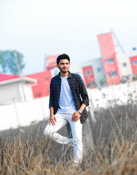 Young man standing on field against sky