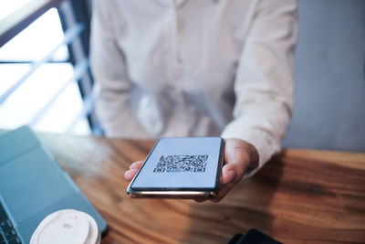 Midsection of man using mobile phone on table