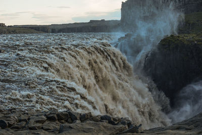 Scenic view of waterfall against sky