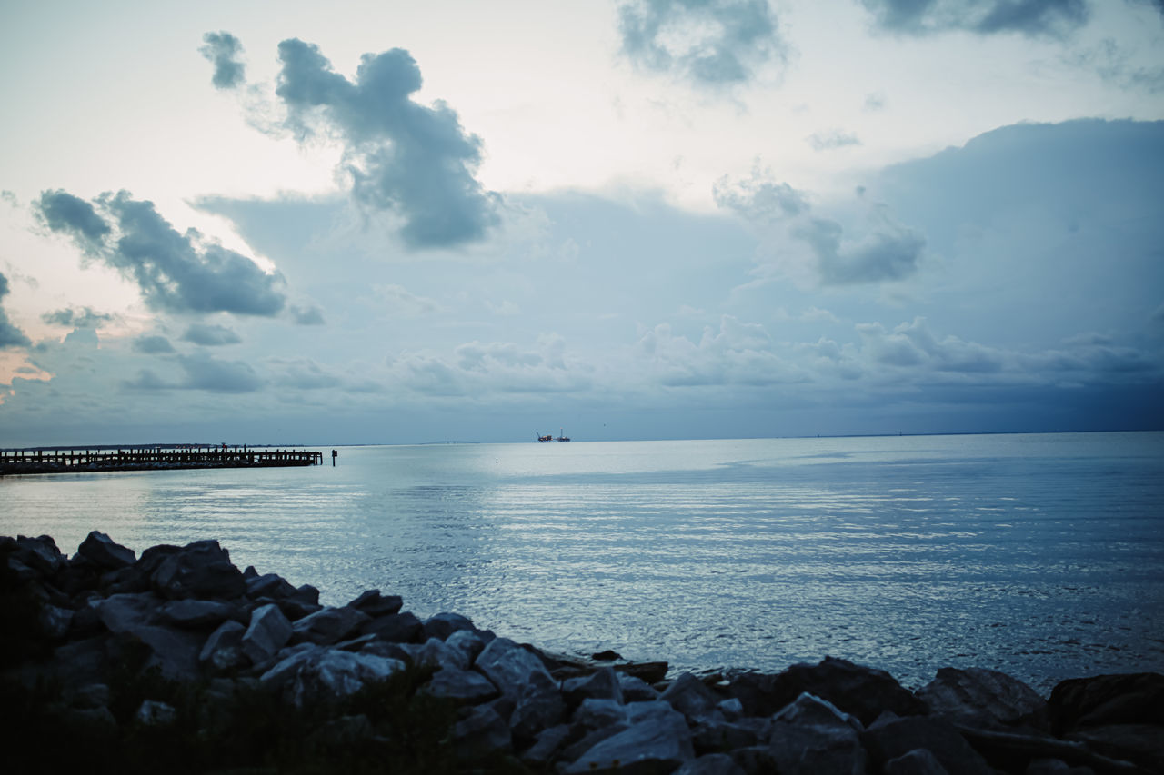 ROCKS BY SEA AGAINST SKY