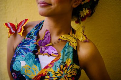 Midsection of woman with artificial butterfly against wall