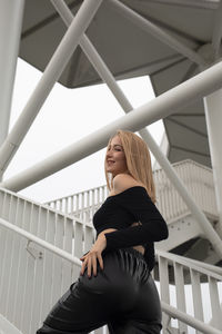 Young woman standing on railing