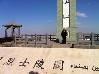 Woman standing by text against sky