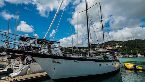 Boats moored at harbor against sky