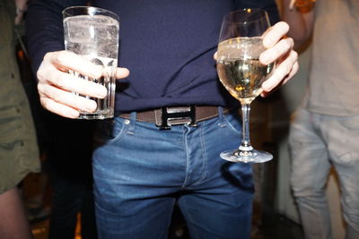 Midsection of man holding wine glass