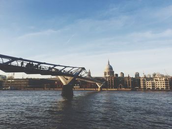 London millennium footbridge over thames river against sky in city