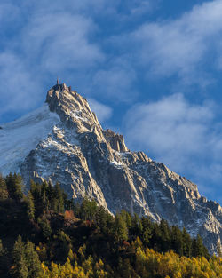 Sunset hitting the side of a mountain with forest in foreview