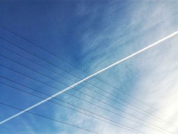 Low angle view of vapor trails against blue sky