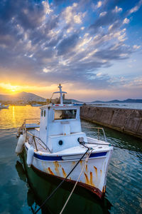 Boat moored on sea against sky during sunset