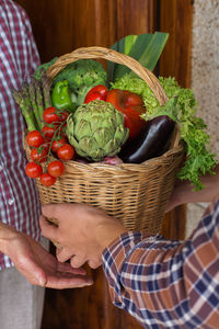 Midsection of person holding vegetables in basket