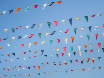 Low angle view of multi colored flags against blue sky