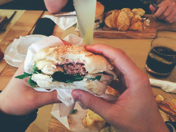 Cropped hands of person having burger at table