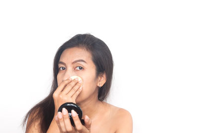 Portrait of young woman holding camera over white background