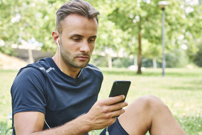 Man with his smart phone sitting on the grass in a park after training. healthy and healthy life. health and sport concept. person