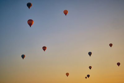 Flying hot air balloons against bright blue and yellow dawn sky