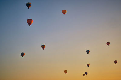 Low angle view of hot air balloons flying against sky during sunset