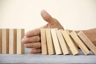 Close-up of hand holding wood against white background