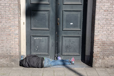 Man sleeping by closed door of building