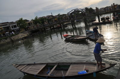 Man on boat moored on river against sky