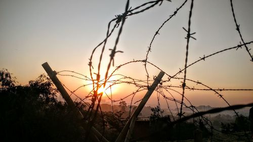 Scenic view of sunset and barbed wire