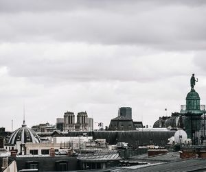 Buildings in city against cloudy sky