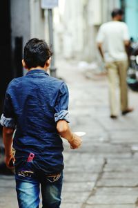 Rear view of father walking with umbrella