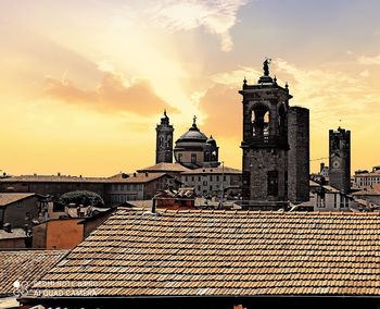 Tower amidst buildings against sky during sunset