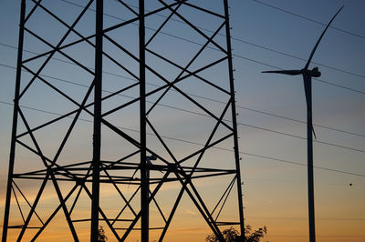 Low angle view of electricity pylon against sky during sunset