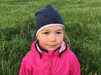 Girl with mud stains on jacket and face standing in field