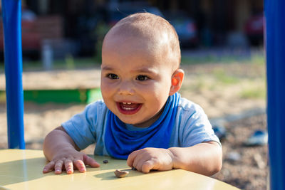 Cute happy smiling baby boy playing at children playground outdoors