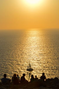 Silhouette of people on sea during sunset