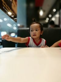 Baby girl sitting at table in restaurant