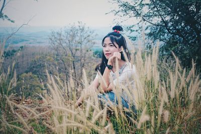 Thoughtful woman crouching on grassy field