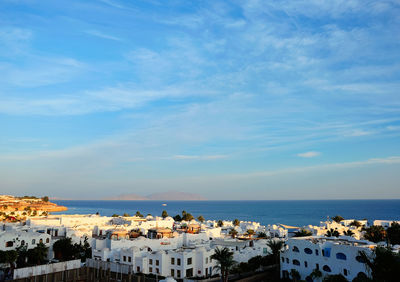 Scenic view of sea by buildings against sky