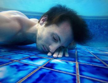 Shirtless man with eyes closed in swimming pool