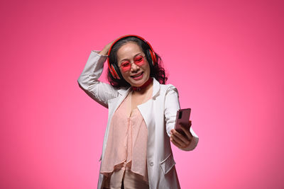 Portrait of young woman standing against yellow background