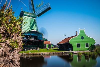 Traditional windmill by building against clear blue sky