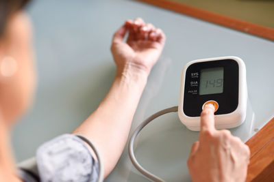 Cropped hands of mature woman examining blood pressure at home