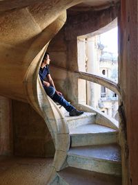 Man sitting on spiral staircase by window